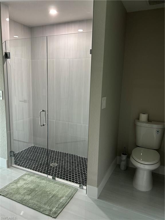 Spacious shower with clear glass enclosure and black hexagonal tile flooring