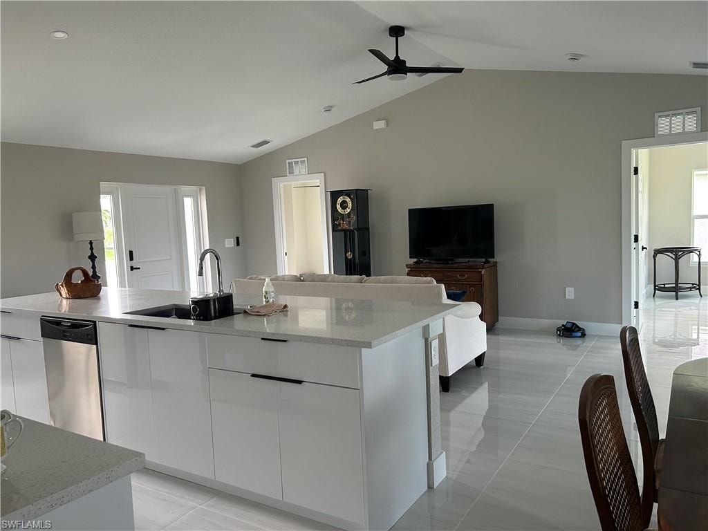 Modern kitchen island featuring a stainless steel dishwasher, an undermount sink with a gooseneck faucet, and white slab-front cabinetry with linear pulls
