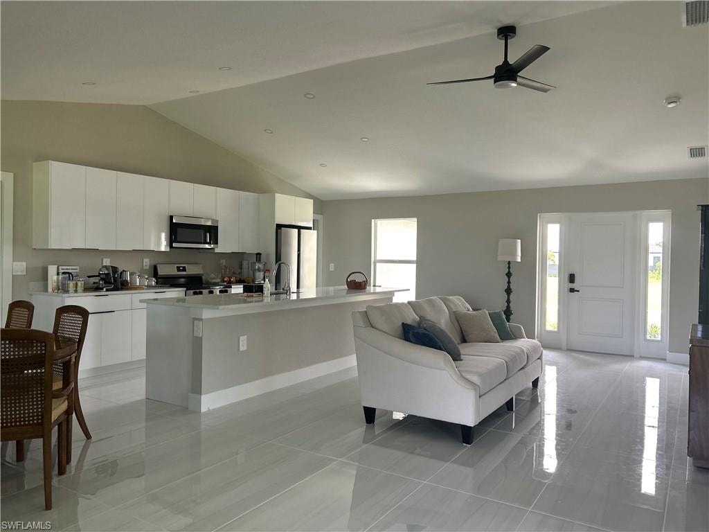 Open-concept living space featuring a vaulted ceiling and light-toned tile flooring