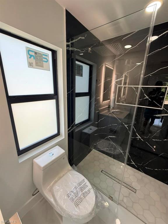Modern bathroom featuring a frameless glass shower enclosure with hex tile flooring and a linear drain