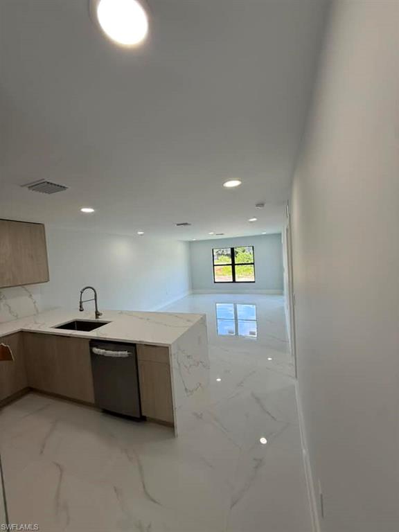Open-concept kitchen and living area featuring a large island with an undermount sink and gooseneck faucet