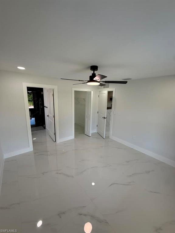 Spacious room featuring large format tile flooring with subtle veining, a ceiling fan with integrated lighting, recessed ceiling lighting, and crisp white walls and trim