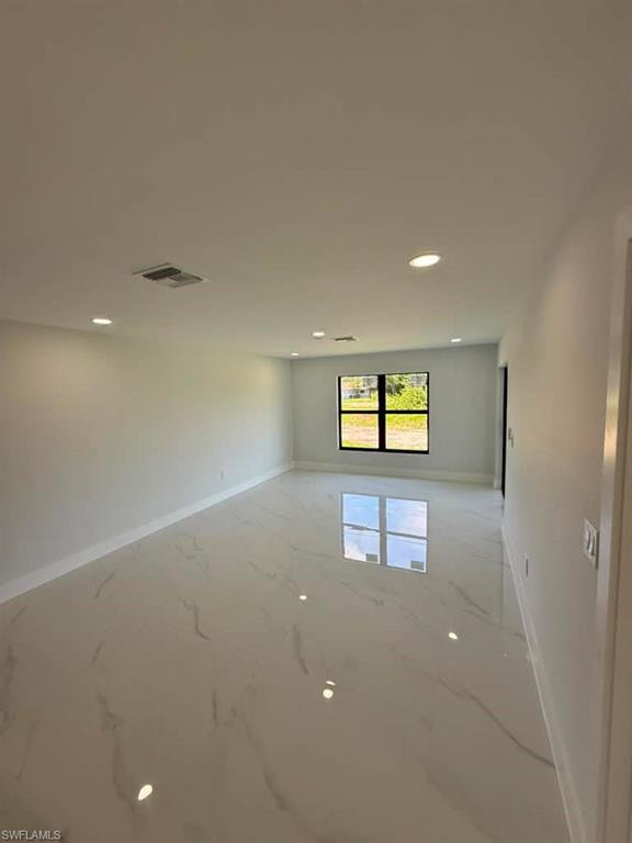 Spacious room featuring large format porcelain tile flooring, recessed ceiling lighting, a modern black-framed window, and crisp white baseboards