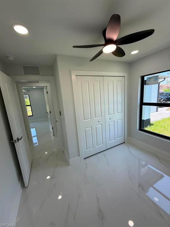 Room featuring white tile flooring with subtle veining, a modern ceiling fan with integrated lighting, recessed lighting, and a window with black trim