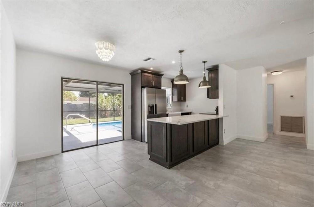 Expansive living space featuring large format tile flooring and direct access to the screened-in patio and swimming pool