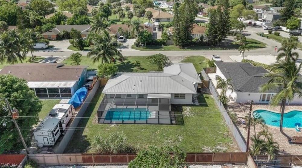 Single-story residence featuring a metal roof, screened pool enclosure, and a spacious backyard with green lawn