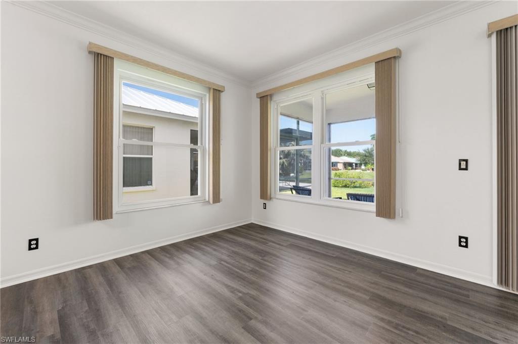 Bright room featuring wood-finish flooring, white walls, and crown molding