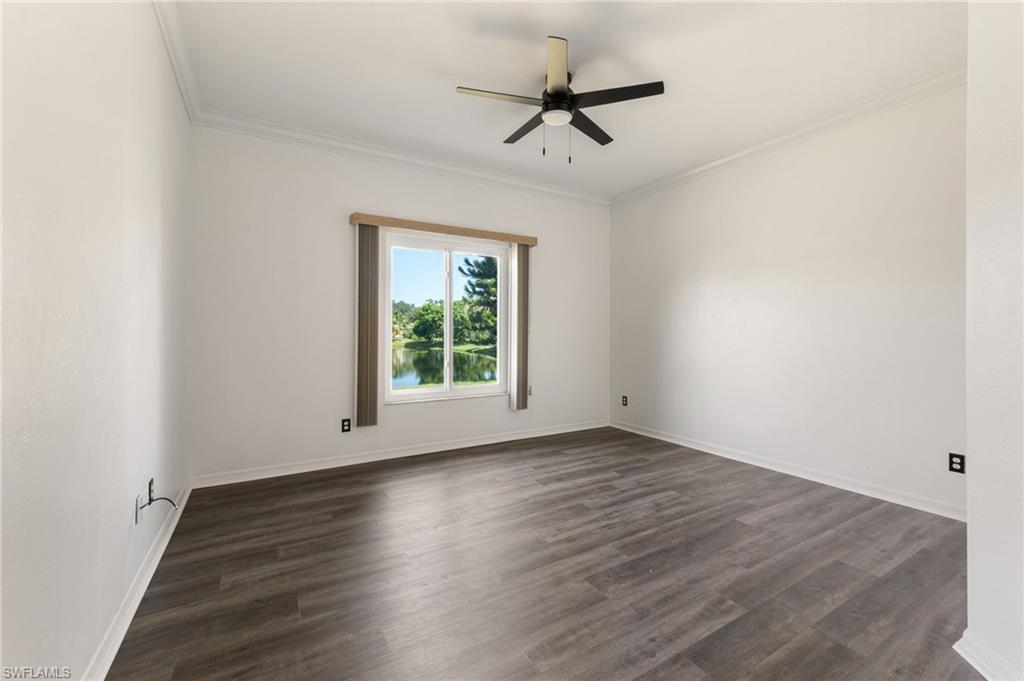 Spacious room featuring wood-finish flooring, crisp white walls, and a contemporary ceiling fan