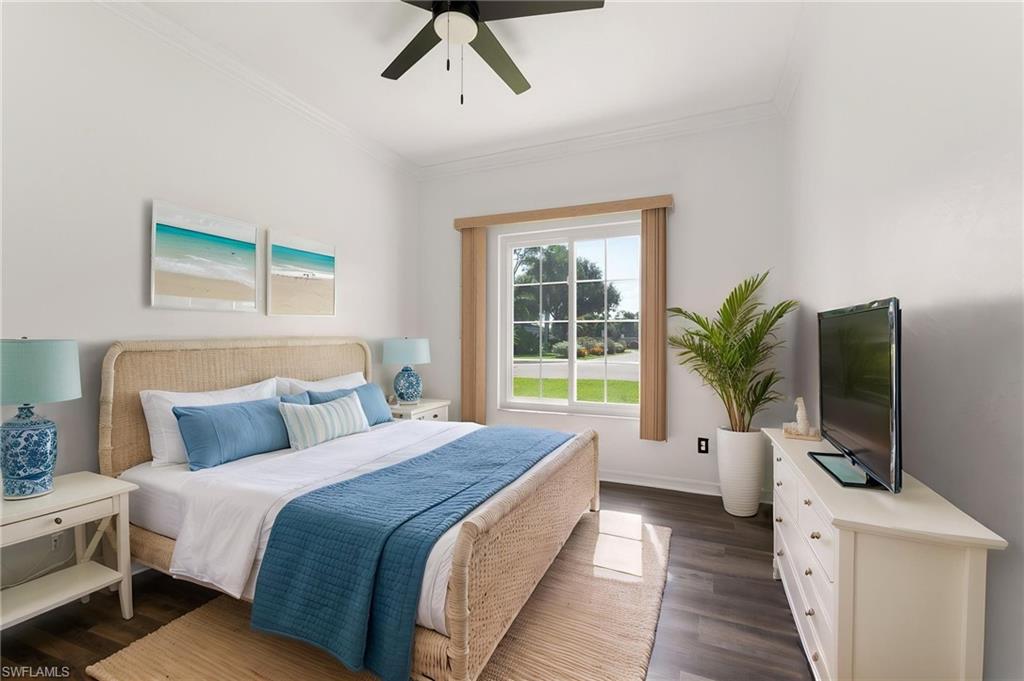 Spacious room featuring wood-finish flooring, a ceiling fan, and white walls with crown molding