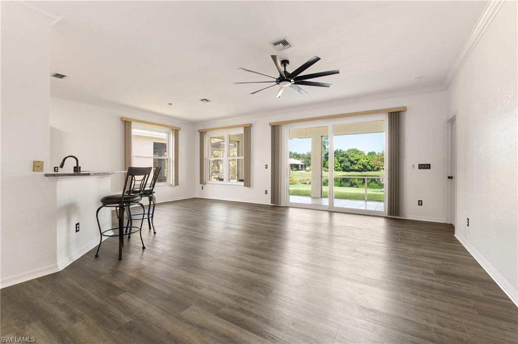 Spacious open-concept interior featuring wood-finish flooring, crown molding, and a modern ceiling fan