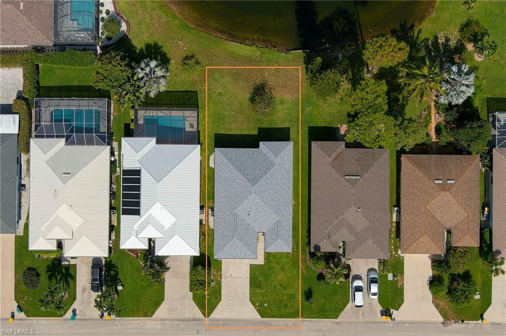 Aerial perspective showcasing a parcel with a residential structure, green lawn, and a paved driveway