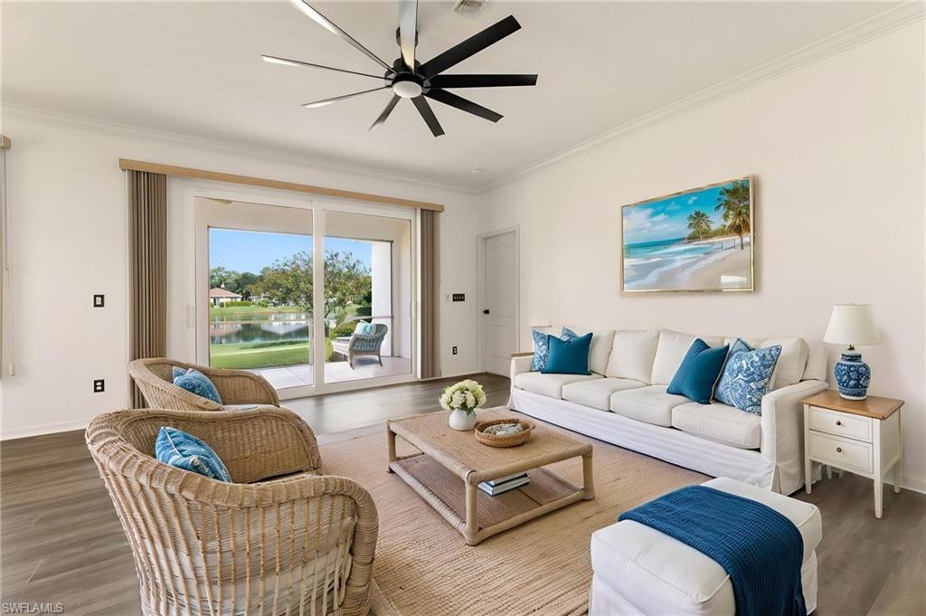 Spacious living area featuring wood-finish flooring, a contemporary ceiling fan, and crown molding