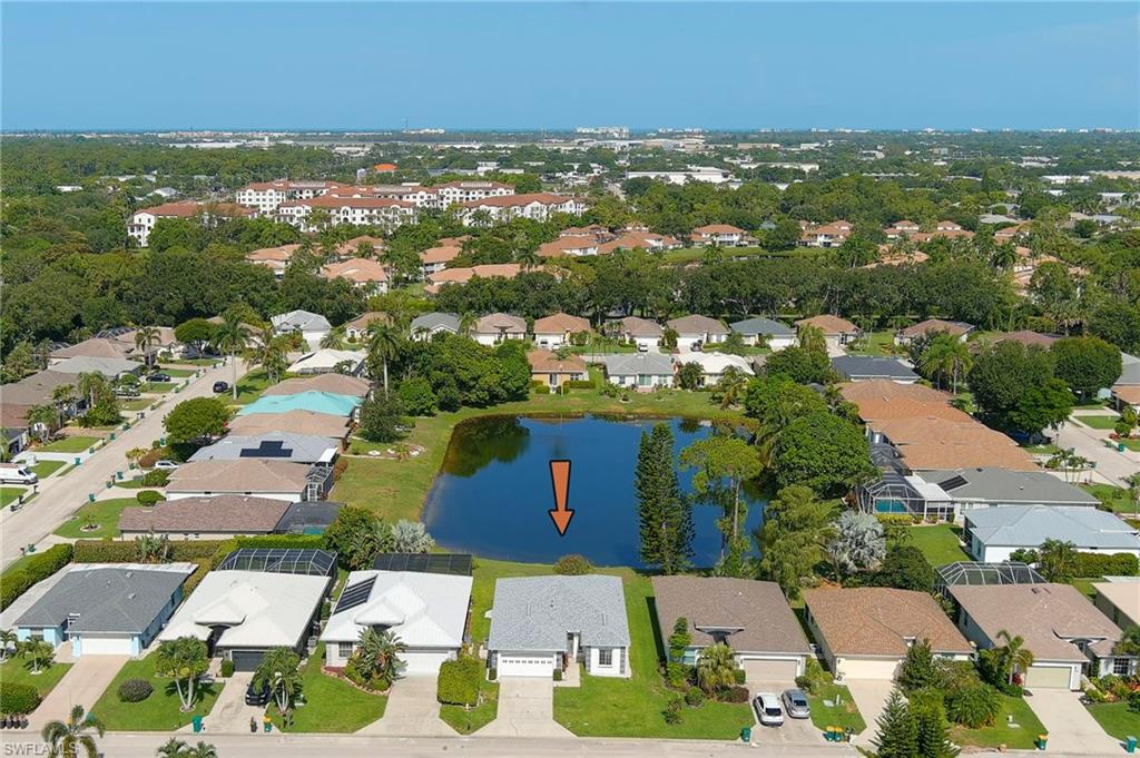Aerial perspective showcasing a residential community with a central pond