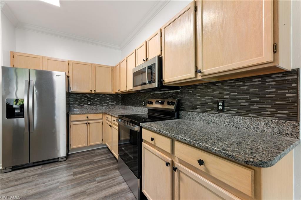 Kitchen featuring light wood cabinetry, stone-finish countertops, and a mosaic tile backsplash