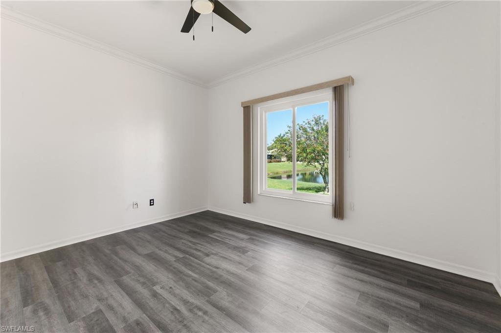 Bright interior space featuring a window with a water feature, wood-finish flooring, a ceiling fan, crown molding, and white baseboards