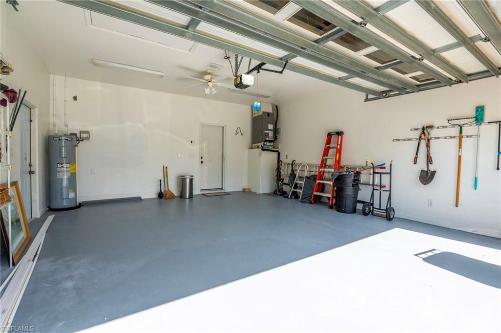 Spacious garage featuring a durable floor coating, fluorescent lighting, a ceiling fan, and accessible utility connections