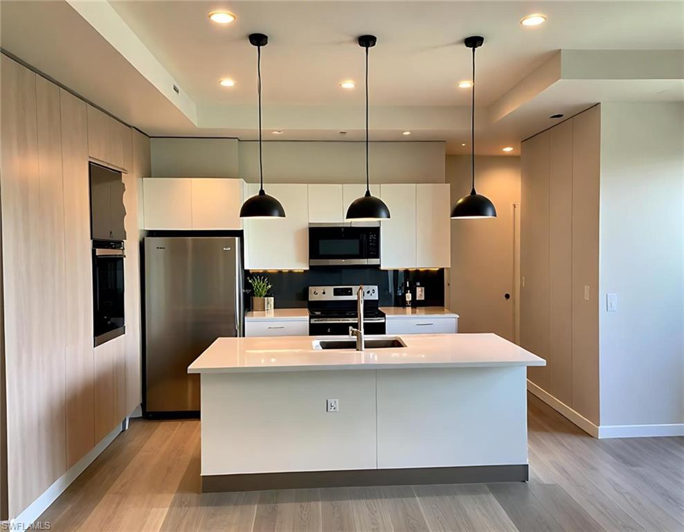 Recessed lighting illuminates a tray ceiling and white walls