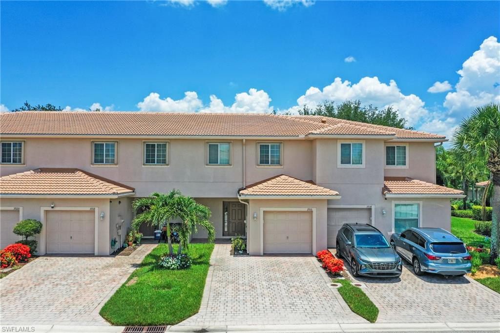 Multi-unit residence featuring a neutral exterior, tile roofing, and multiple windows