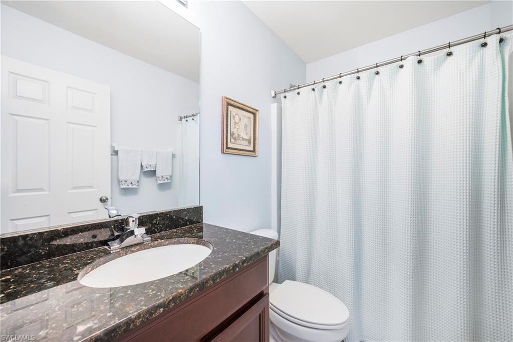 Bathroom featuring a vanity with an integrated oval sink, a dark speckled countertop, and a chrome faucet