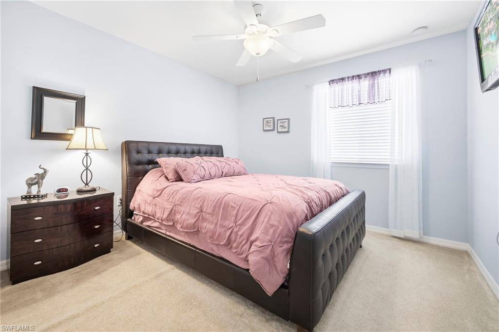 Carpeted bedroom with light blue walls, featuring a window with white blinds and sheer curtains