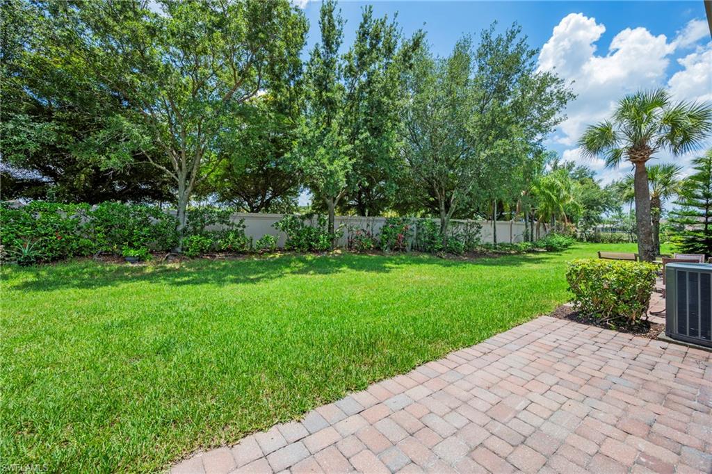 Expansive backyard with verdant lawn, mature trees, and a paver patio
