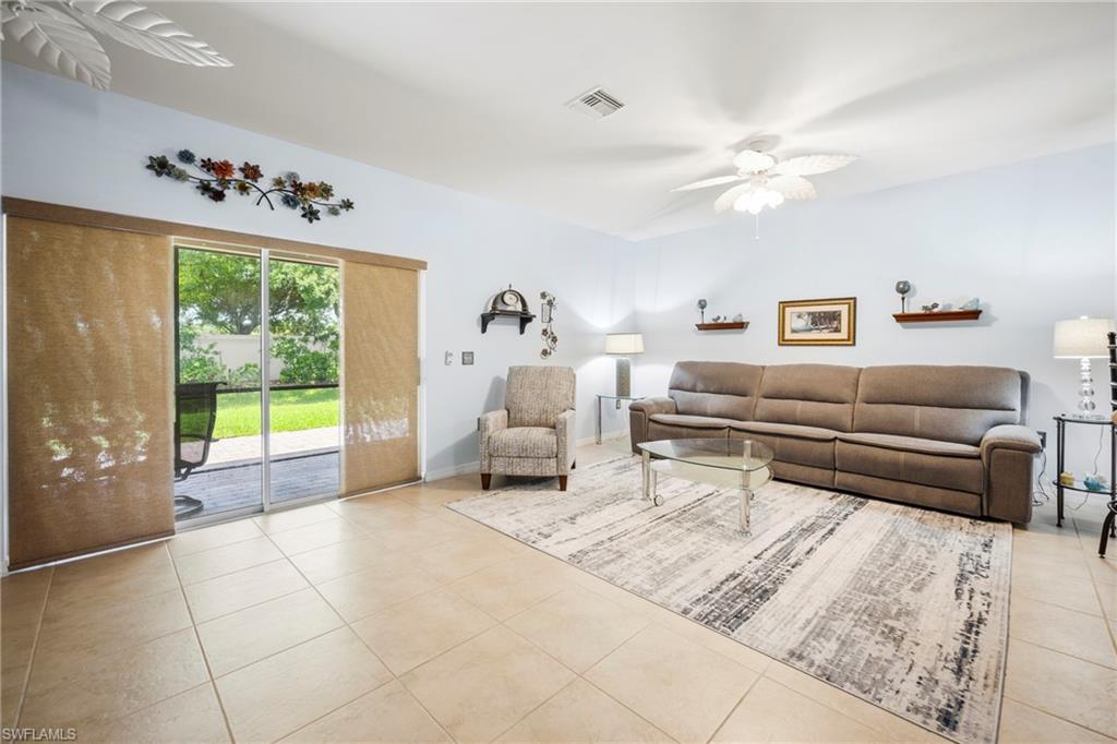 Spacious living area featuring neutral tile flooring, light-toned wall paint, and a white ceiling fan
