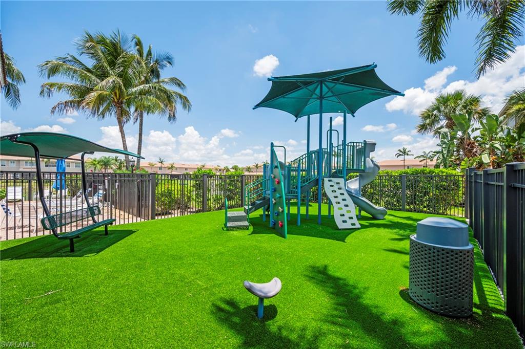 Recreational area featuring a playground structure with slides and climbing elements, a covered swing, and artificial turf surfacing