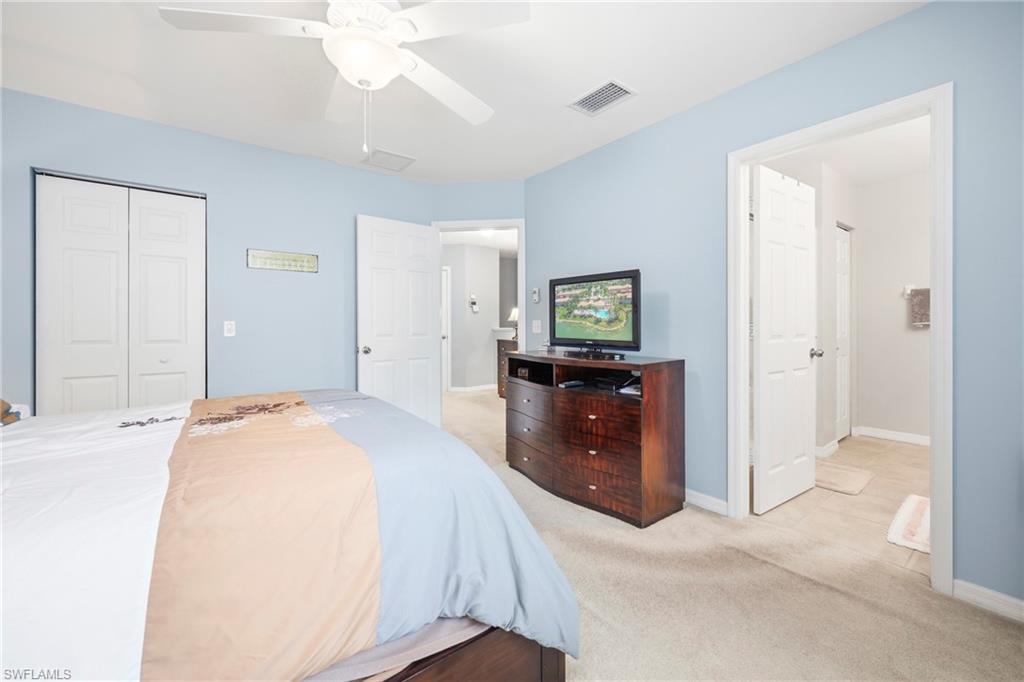 Carpeted bedroom with a ceiling fan, light blue walls, and white bi-fold closet doors