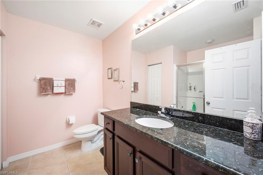 Bathroom featuring a dark-toned vanity with an integrated sink, a speckled countertop, and a large wall-mounted mirror