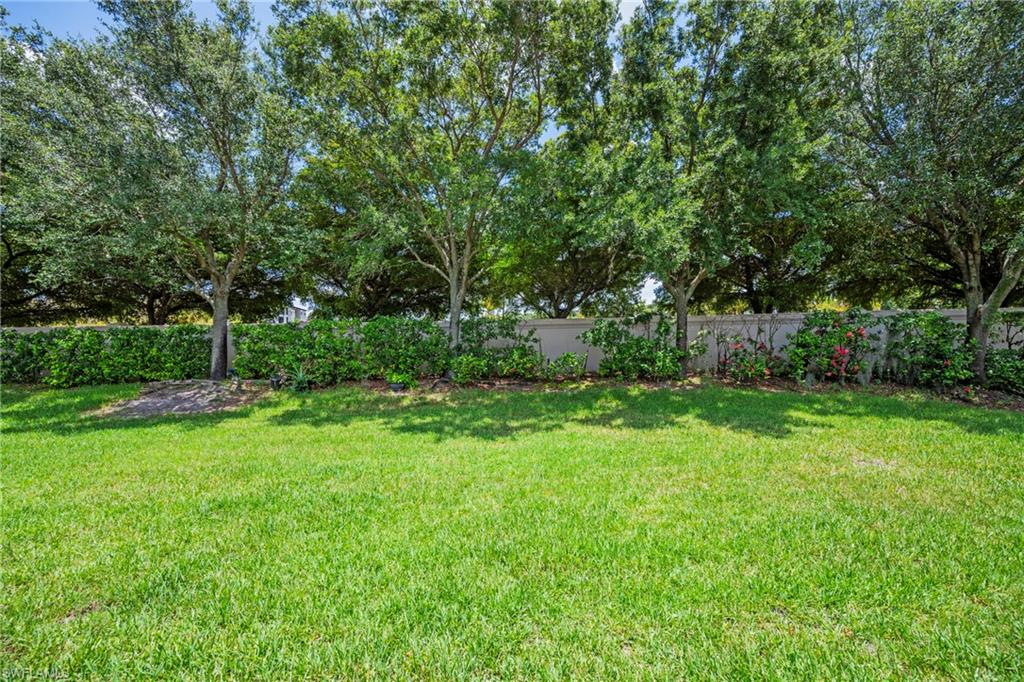 Expansive green lawn framed by mature trees and a privacy hedge