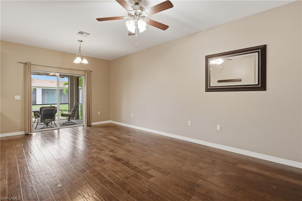 Spacious room featuring wood-finish flooring, light tan walls, and white baseboards