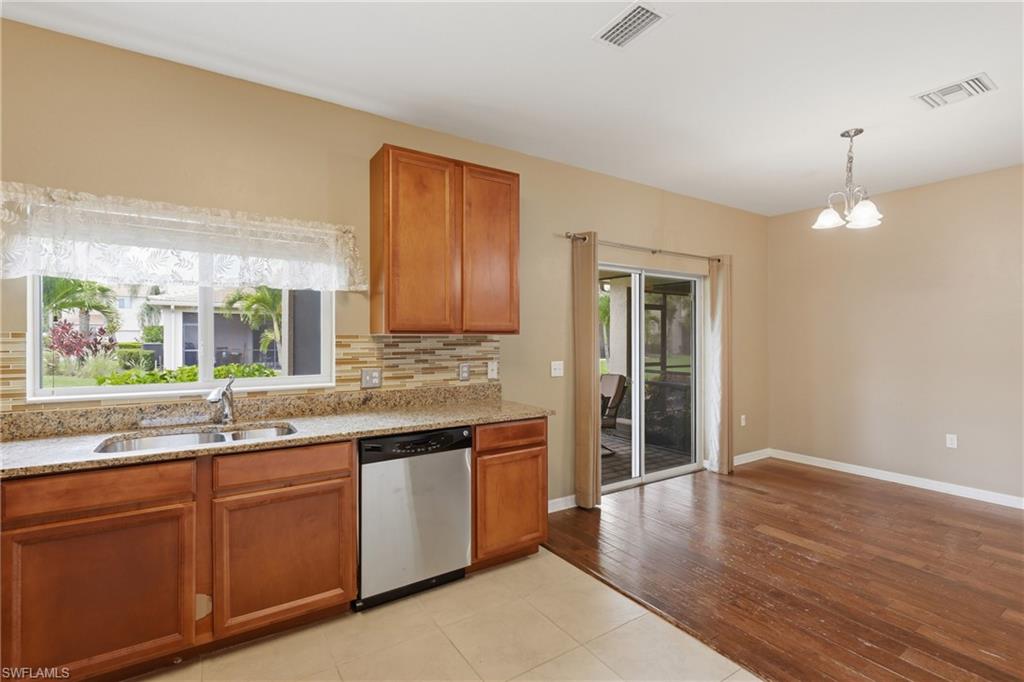 Kitchen area featuring wood cabinetry, stone countertops, a stainless steel dishwasher, and a tile backsplash