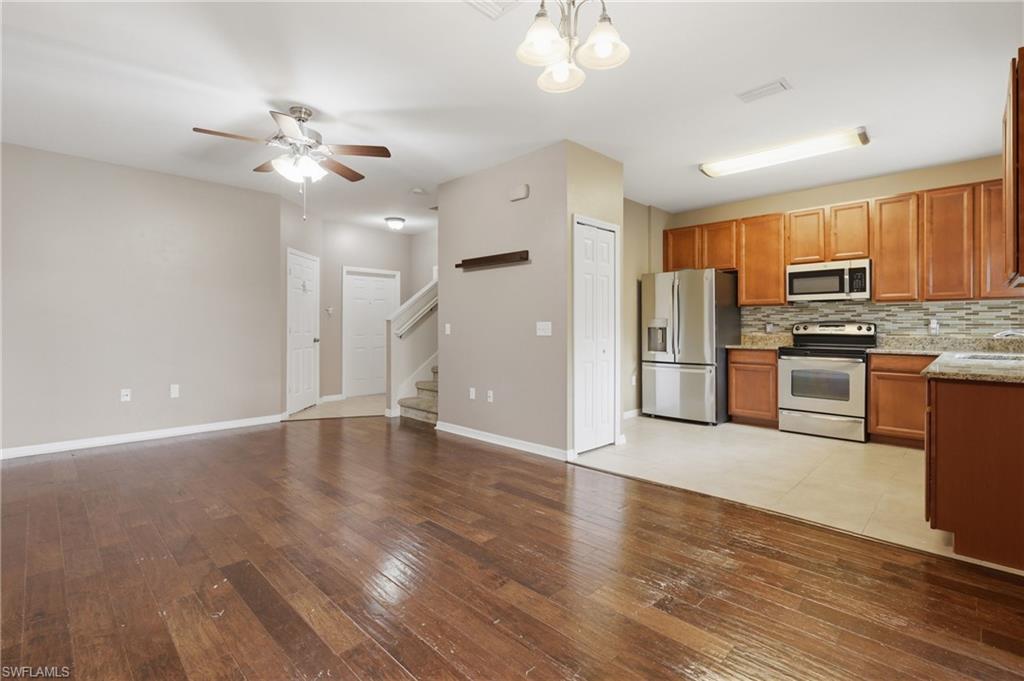 Open-concept layout featuring wood-finish flooring, a kitchen with stainless steel appliances, light wood cabinetry, and a mosaic tile backsplash