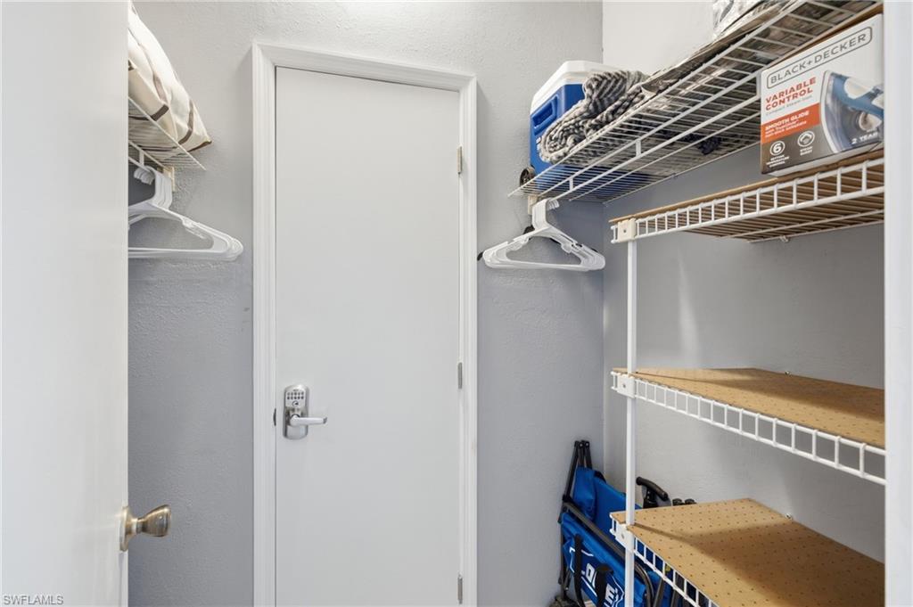 Storage closet featuring white wire shelving, a hanging rod, and light gray wall paint - Virtually Edited Image