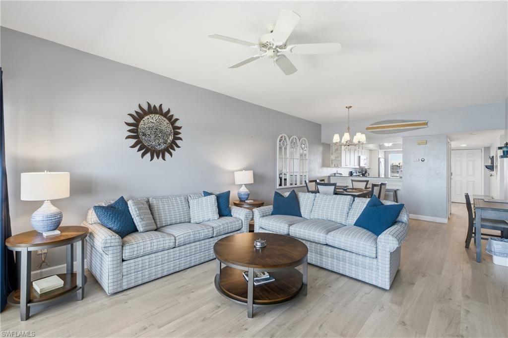 Open-concept living area featuring light wood-finish flooring, a vaulted ceiling with a ceiling fan, and recessed lighting - Virtually Edited Image