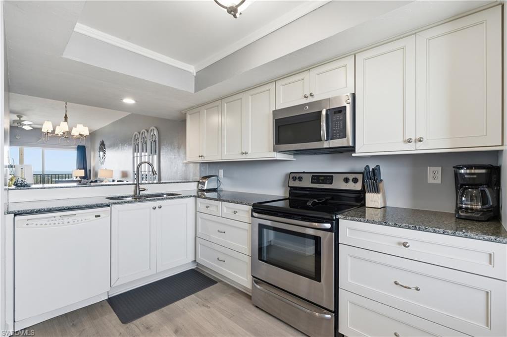 Modern kitchen featuring white cabinetry, granite countertops, and wood-finish flooring - Virtually Edited Image