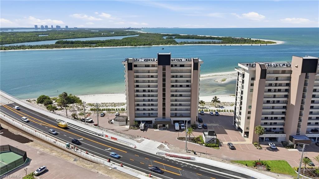 Multi-story building directly fronting a sandy beach and expansive body of water - Virtually Edited Image