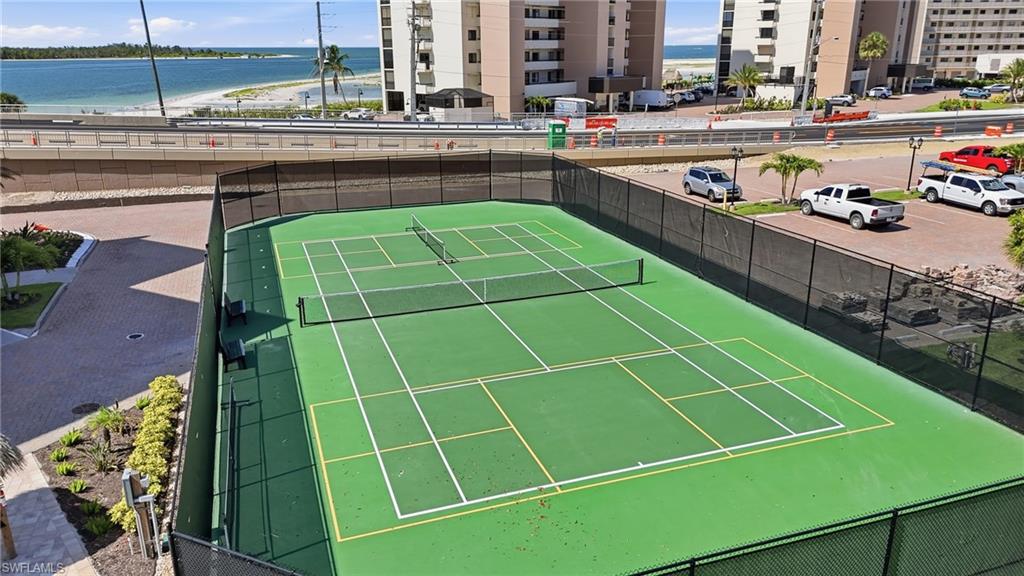 Full-size tennis court featuring a green playing surface with white and yellow court lines - Virtually Edited Image