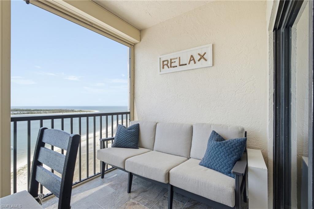 Balcony featuring expansive water and beach vistas, textured exterior wall, and tile flooring - Virtually Edited Image