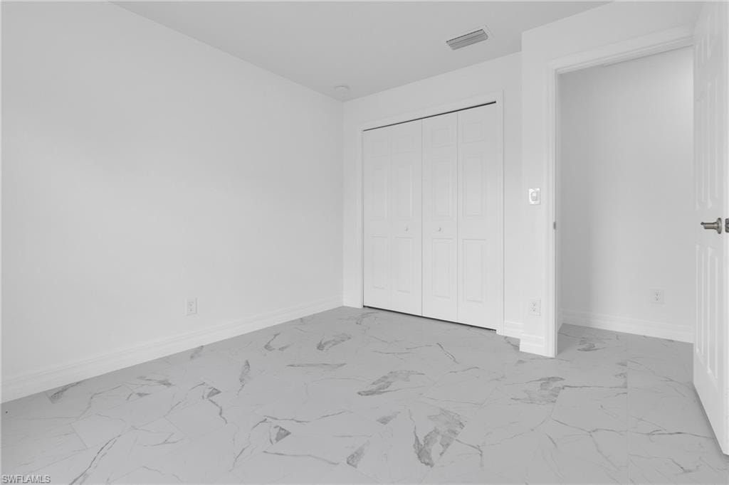 Room featuring white walls and marble-look tile flooring