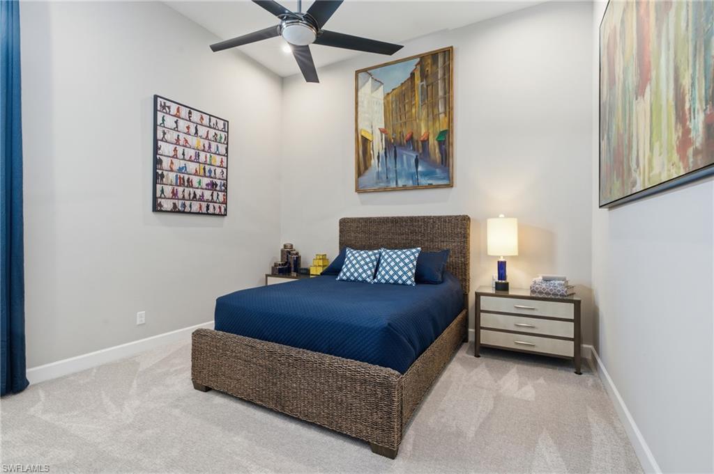 Carpeted room featuring light gray walls, a ceiling fan, and tall baseboards