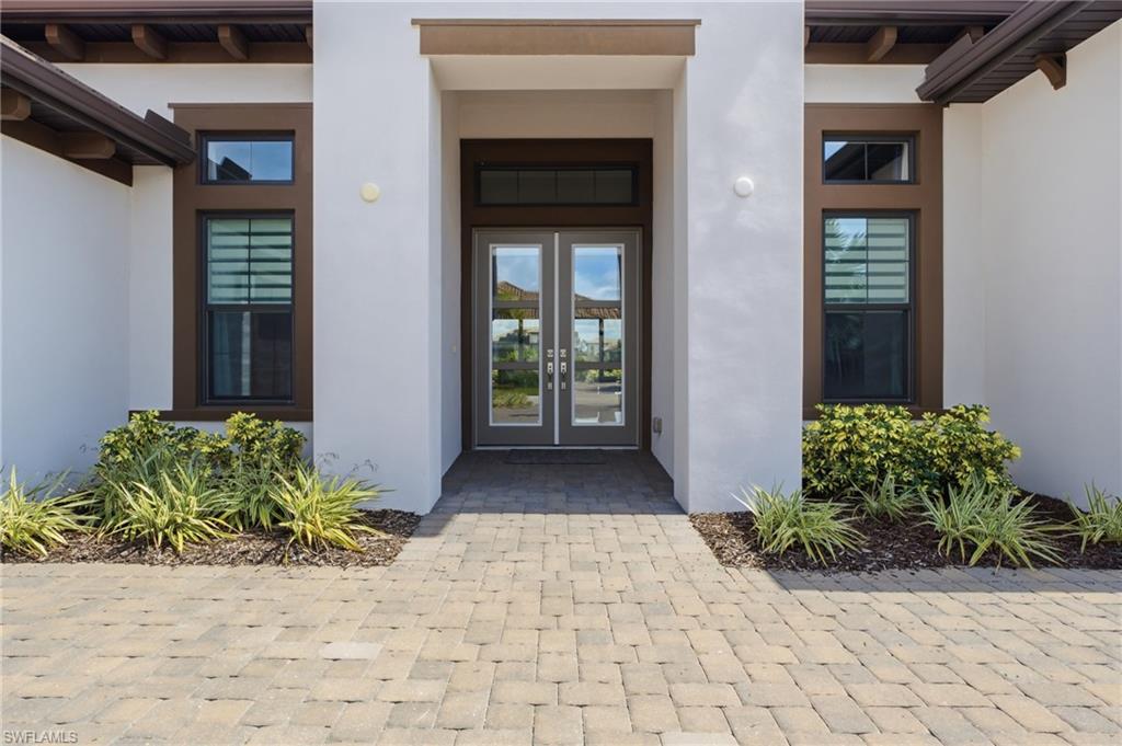 Paver driveway and walkway leading to a double-door entry with transom window