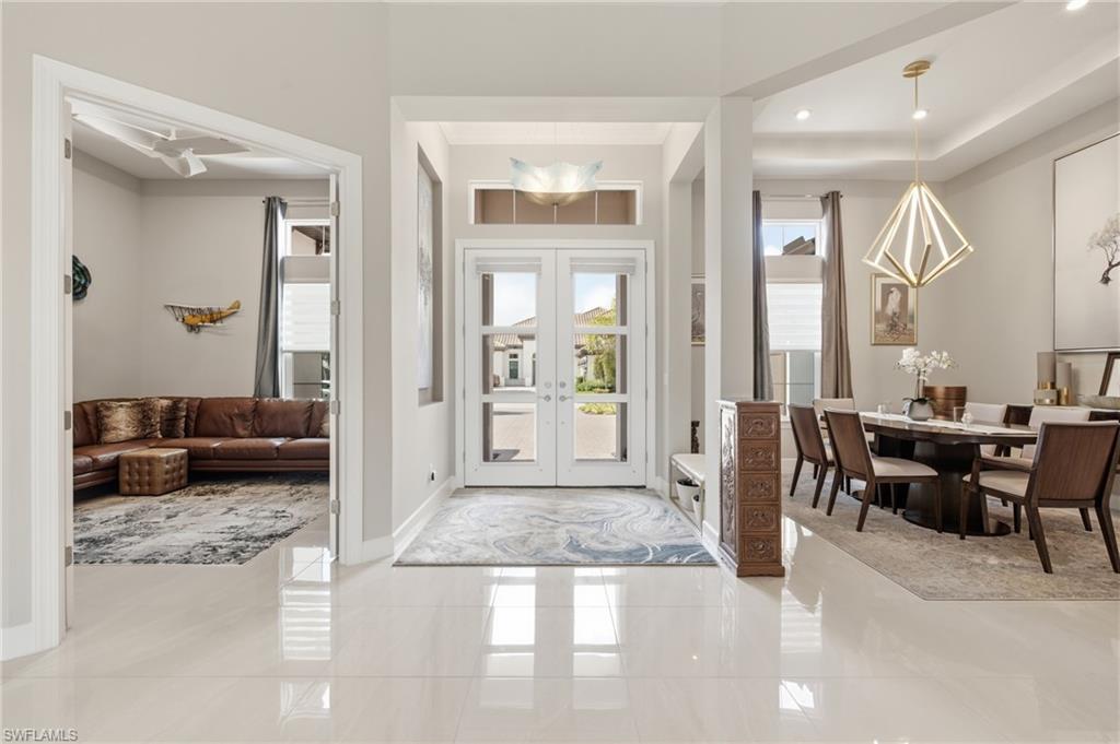 Grand entryway featuring polished tile flooring, double glass-paneled entry doors, and a decorative transom window