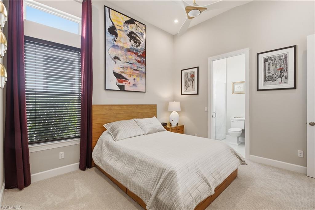 Bedroom featuring a vaulted ceiling with a flush-mount ceiling fan, a large window with horizontal blinds and clerestory window, and light-toned carpet flooring