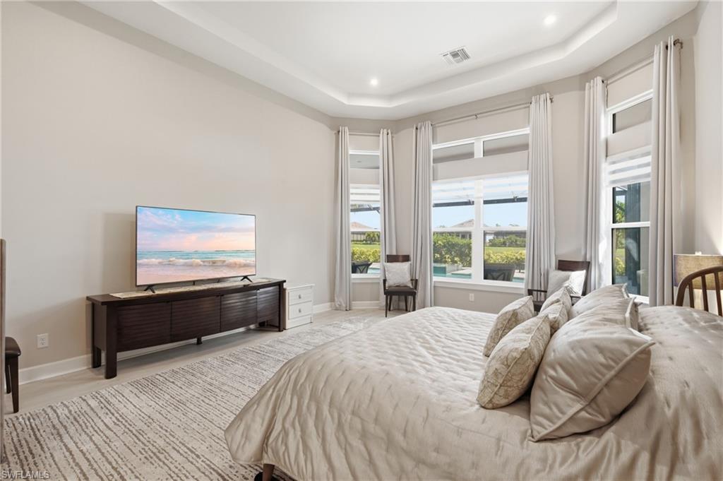 Spacious room featuring a tray ceiling with recessed lighting, light-toned walls, and large windows with privacy blinds