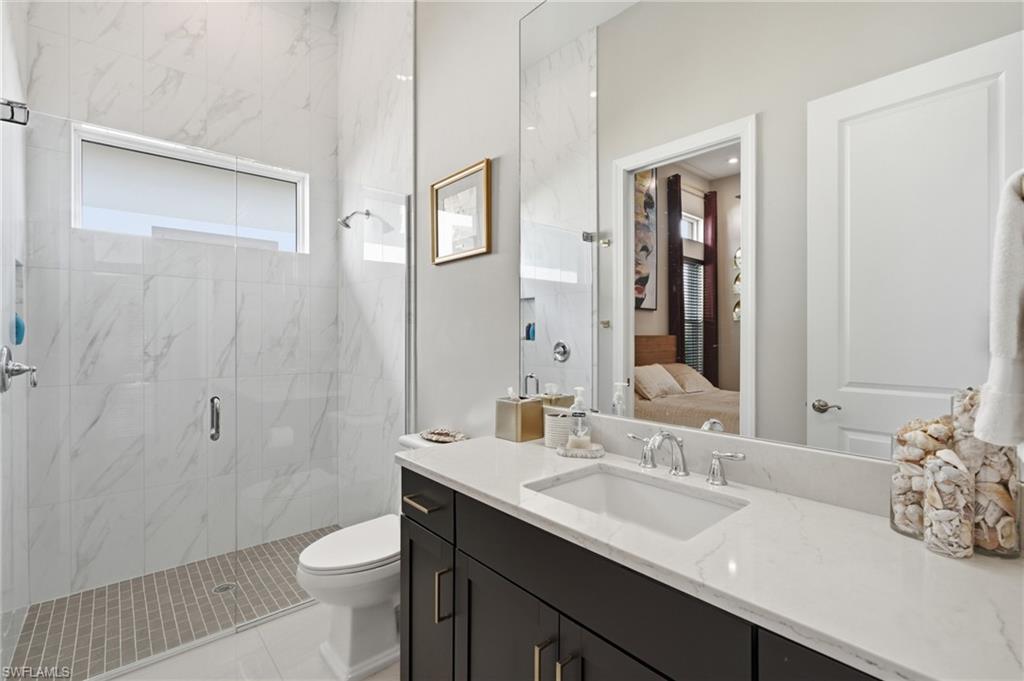 Spacious bathroom featuring a glass-enclosed shower with full-height white marble-look tile, a rectangular transom window, and a mosaic tile shower pan
