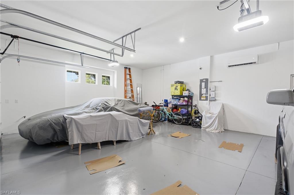 Spacious garage featuring a light gray epoxy floor coating, white walls, and multiple windows for natural light