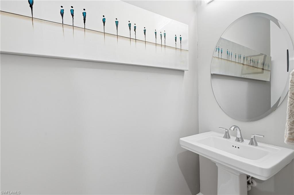 Pedestal sink with chrome fixtures and a beveled oval mirror