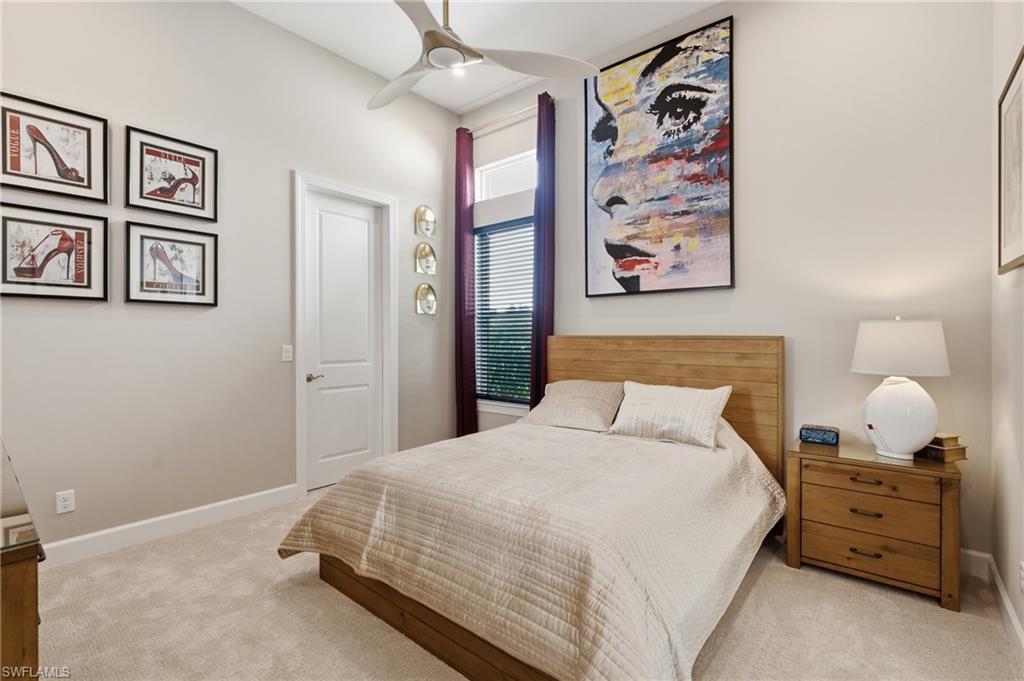 Carpeted room featuring a ceiling fan, a window with horizontal blinds and crimson drapes, and a white interior door
