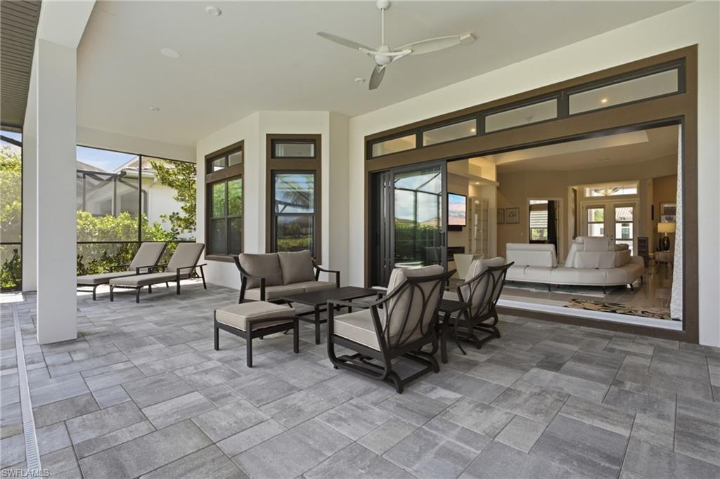 Expansive covered patio featuring large format paver flooring, a ceiling fan, and screened enclosure